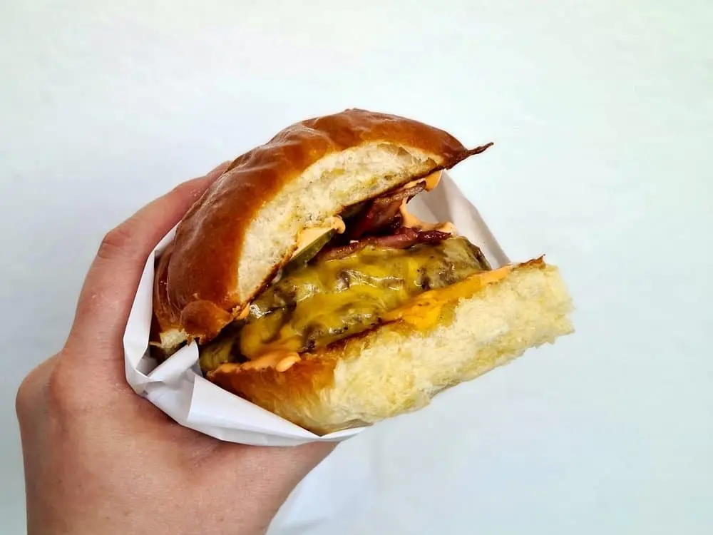 burger v ruce kde je maso se sýrem a slaninou