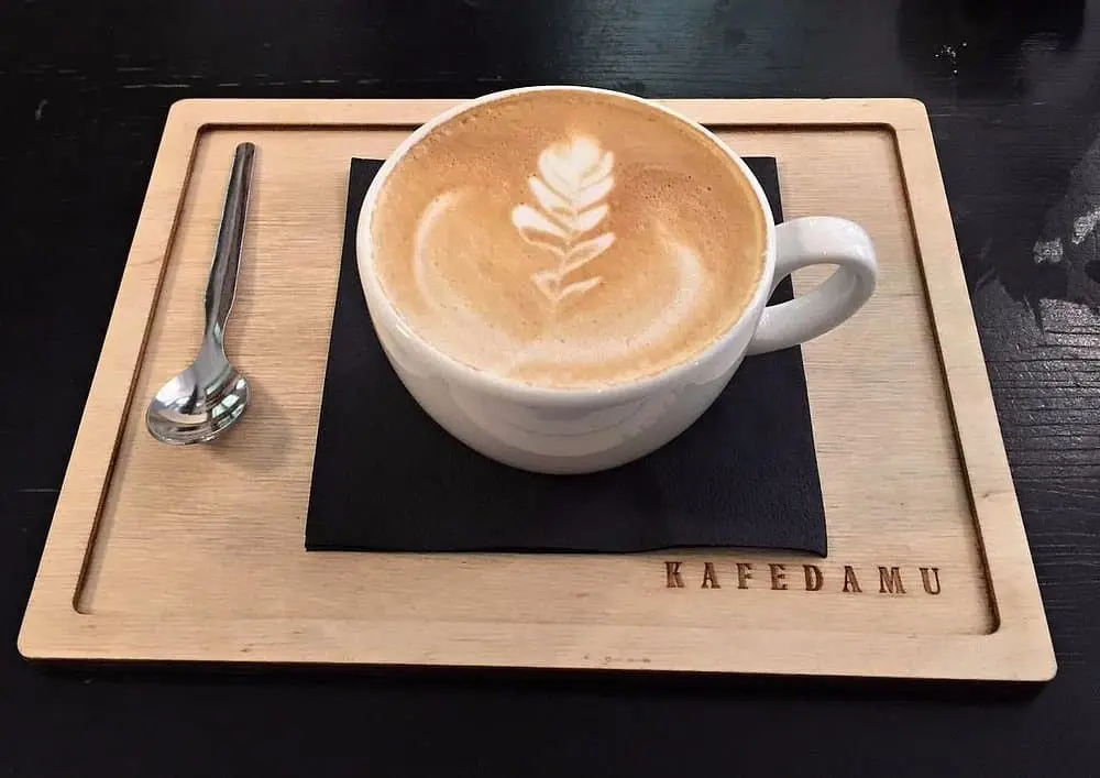 Kafe na dřevěném podtácku kde je vlevo lžička