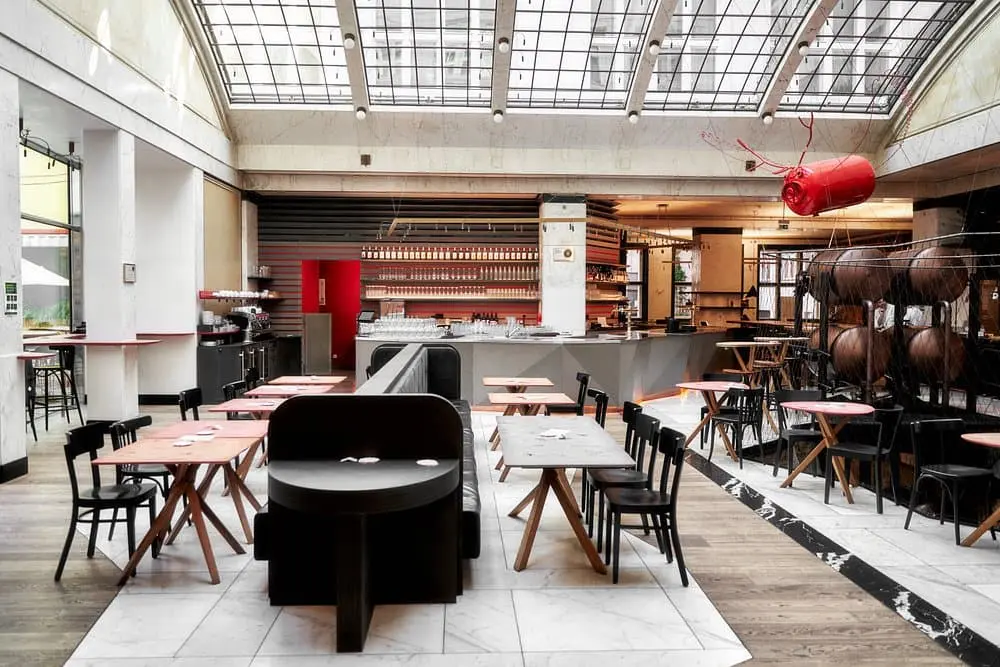 interiér velmi moderní restaurace červený jelen, kde jsou židle a stolky z dřeva. v pozadí je vidět i na bar