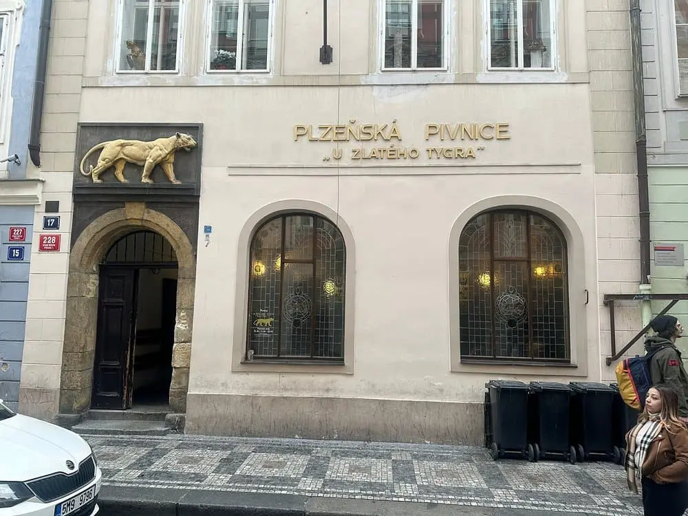 exterier restaurace u zlatého tygra, kde nad vstupem je zlatý tygr a vedle něj je nápis u plzenska pivnice u  zlatého tygra