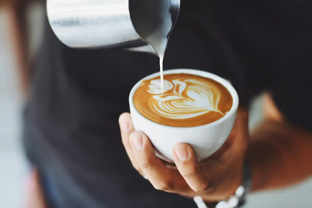 Fotografie kafe, kde obsluha dělá kafe-art 